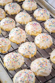 iced cookies with white frosting and sprinkles are cooling on a rack