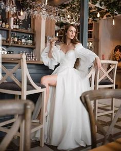 a woman in a white dress sitting at a bar