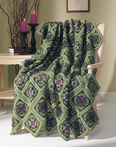 a green crocheted blanket sitting on top of a chair next to a table