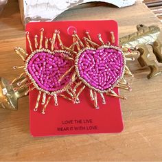 two pink heart shaped earrings sitting on top of a red card with the words love the line wear it with love