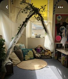 a living room with a couch covered in pillows and plants next to a large window