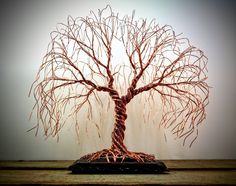 a wire tree sculpture sitting on top of a wooden table