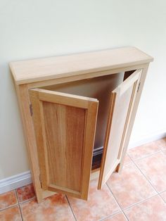 a wooden cabinet sitting on top of a tiled floor next to a wall with a door open