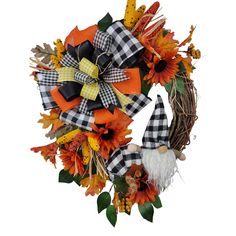 a wreath with an orange, black and white plaid bow on it that has a gnome in the center