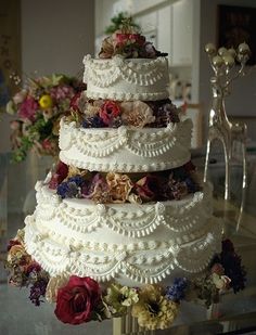 a wedding cake sitting on top of a glass table next to vases filled with flowers