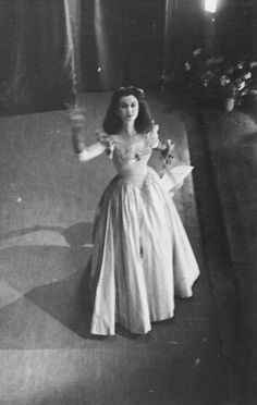 an old black and white photo of a woman in a long dress with her arms outstretched