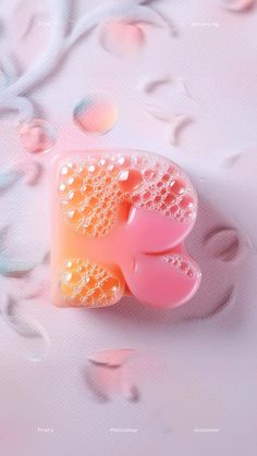 a pink and orange soap dish sitting on top of a white surface with flowers in the background