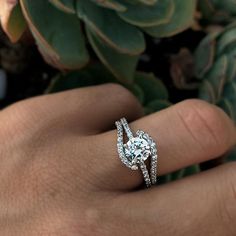 a woman's hand with a diamond ring on it and succulents in the background