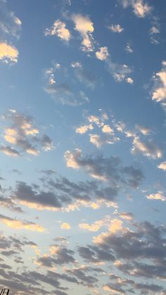 an airplane is flying high in the sky with clouds above it and some telephone poles