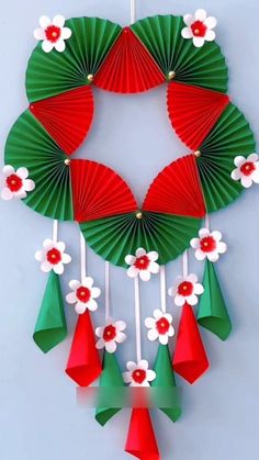 an origami christmas wreath with red and green paper fans hanging from it's sides