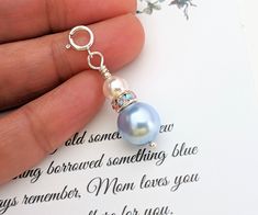 a hand holding a key chain with a blue pearl