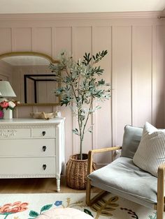 a white dresser sitting next to a mirror on top of a wooden floor in a living room