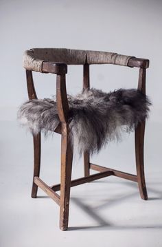 a wooden chair with a furry seat pad on it's armrest and back