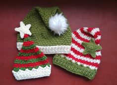 crocheted hats and mittens are sitting on a red surface with white pom - pom