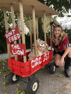 a woman and child in a wagon with signs on the wheels that say don't feed the lion