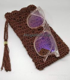 a pair of glasses sitting on top of a crocheted case next to a tassel