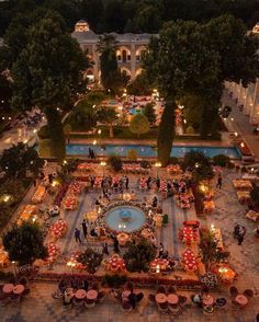 an aerial view of a garden with tables and umbrellas in the center at night