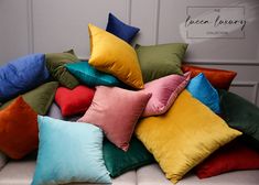 a pile of colorful pillows sitting on top of a white couch next to a wall