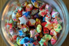 a glass bowl filled with lots of colorful candies on top of a wooden table