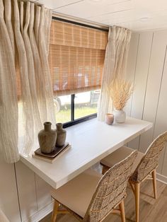 two chairs and a table in front of a window with sheer curtains on the windowsill