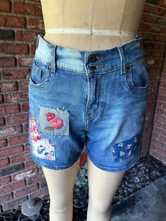 Up-cycled Levi's denim shorts Size 6. Bleached pocket and waist details  hand embroidered flowers denim patch.   waist flat measurements 15" inseam 4 1/2" Short Spring Bottoms With Patchwork, Spring Denim Bottoms With Patches, Casual Patchwork Shorts For Spring, Upcycled Blue Jeans For Summer, Casual Denim Jean Shorts With Floral Embroidery, Patchwork Cotton Jean Shorts For Spring, Fitted Cotton Jean Shorts In Medium Wash, High Waist Recycled Denim Jean Shorts For Spring, Blue Upcycled Jeans For Summer