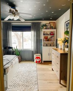 a bedroom with a ceiling fan, bed and dresser in the corner next to a window