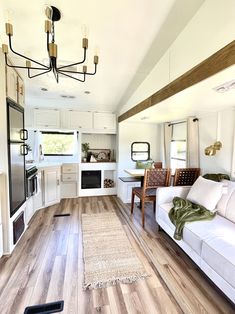 a living room filled with furniture next to a kitchen and dining room table on top of a hard wood floor