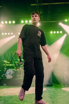 a man standing on stage with a microphone in his hand and green lights behind him