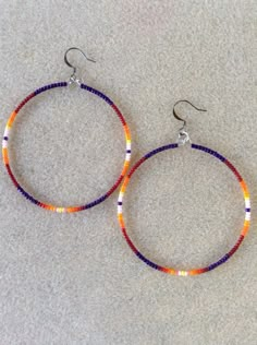 two pairs of beaded hoop earrings sitting on top of a white carpeted floor