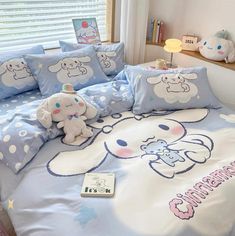 a bed with blue and white comforters, pillows and stuffed animals on the covers