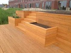 a wooden deck with planters on the side and grass growing out of one end