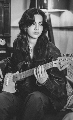 a black and white photo of a woman playing an electric guitar