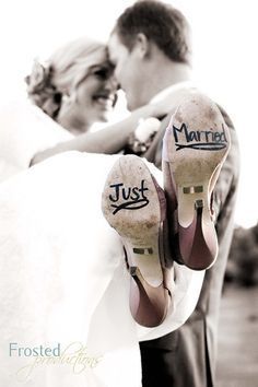 the bride and groom are holding each other close to their wedding shoes with just married written on them