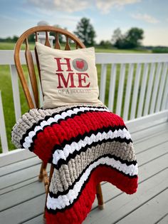 a chair with a pillow on top of it sitting on a porch next to a wooden rocking chair