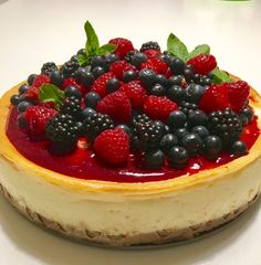 a cheesecake topped with berries and mint leaves