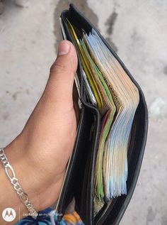 a person holding a wallet full of files