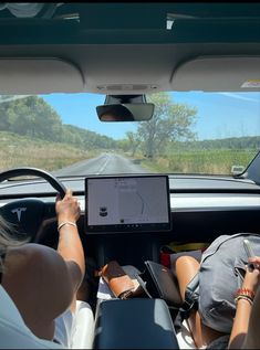 two people sitting in the back seat of a car with a computer on their lap