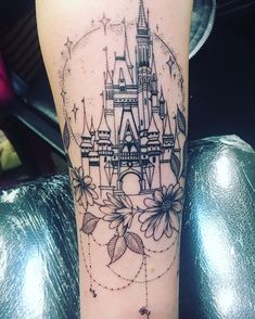 a tattoo on the leg of a woman with a castle and flowers in front of it