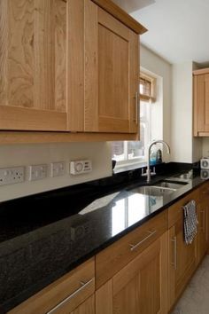 a kitchen with black counter tops and wooden cabinets