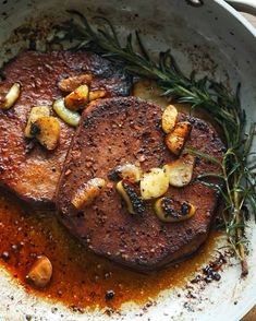 two steaks with mushrooms and sauce in a pan