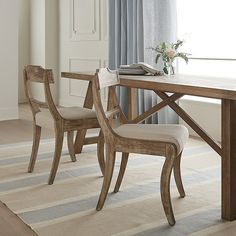 two wooden chairs sitting at a table in front of a window