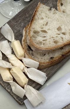 two slices of bread on a cutting board next to buttered cheese and an open knife