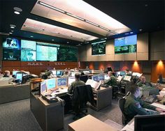 an office filled with lots of computers and people sitting at desks in front of monitors