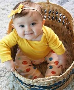 a baby sitting in a basket on the floor