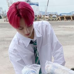 a young man with pink hair wearing a tie and white shirt holding two plastic bags