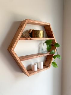 two wooden shelves with candles and plants on them against a white wall in the corner