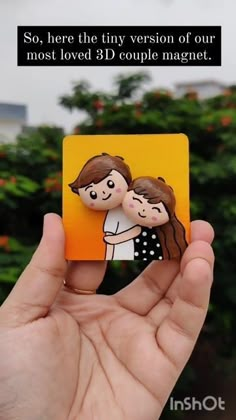 someone is holding up a small magnet with the image of two people hugging each other