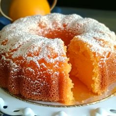 a cake with powdered sugar on top sits on a plate next to an orange