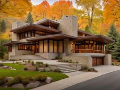 a large modern house in the middle of trees and grass with fall foliage around it