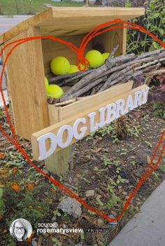 a wooden box filled with tennis balls sitting on top of a grass covered field